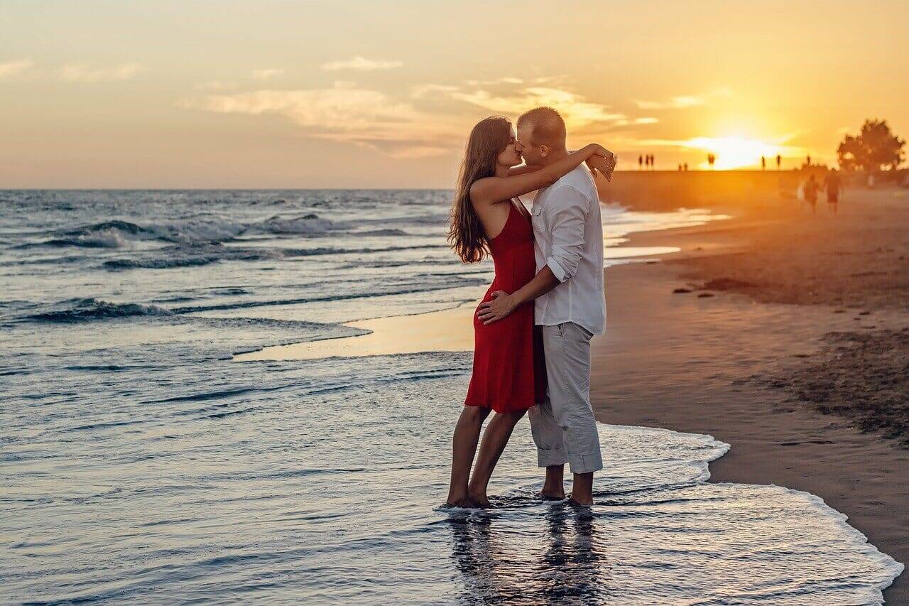 Urlaub machen, junges Paar küsst am Strand